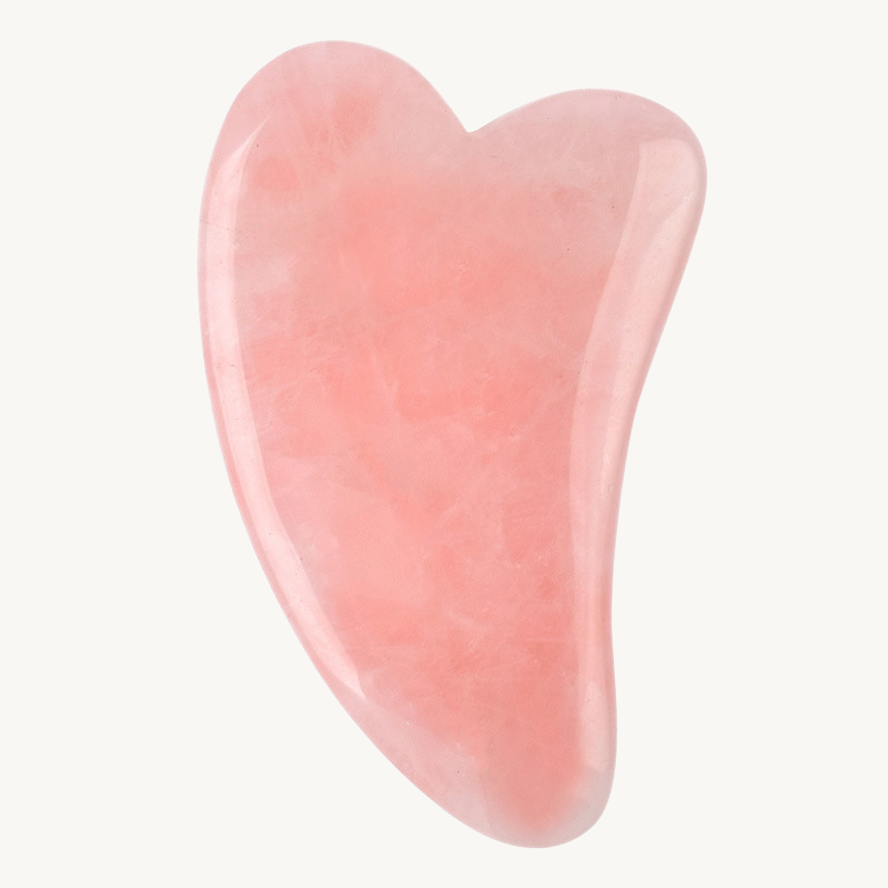 Pink gua sha with a heart shape on a white background